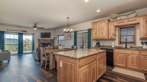 A spacious kitchen with wooden cabinets, a granite countertop island, and a dining area with a view. - 2BR Village At Indian Point 1704 near SDC - Free Tickets Daily up to $500 (Branson)