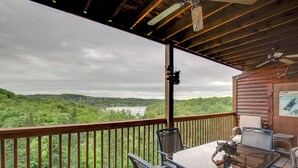 A wooden deck with a glass table and chairs overlooking a lake and forest. - 2BR Village At Indian Point 1705 near SDC - Free Tickets Daily up to $500 (Branson)