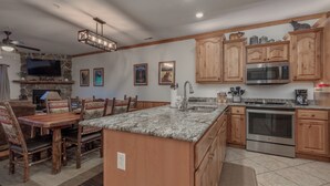 A spacious kitchen with wooden cabinets, a granite countertop, a built-in oven, and a large island. - 2BR Village At Indian Point 1706 near SDC - Free Tickets Daily up to $500 (Branson)