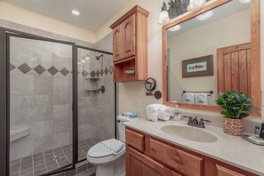 Ein Badezimmer mit Dusche, Toilette, Waschbecken und Holzschränken.