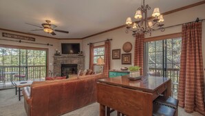 A spacious living area with a fireplace, wooden furniture, and large windows. - 2BR Village At Indian Point 1904 near SDC - Free Tickets Daily up to $500 (Branson)