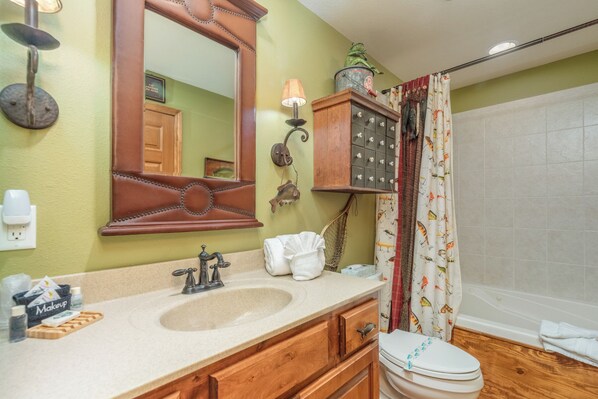 A bathroom with a wooden vanity, a large mirror, a sink, and a toilet.