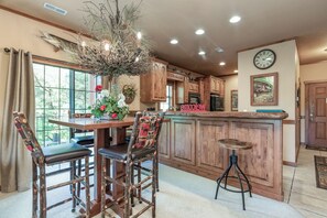 A kitchen with wooden cabinets, a dining table with chairs, a bar stool, and a decorative plant centerpiece.