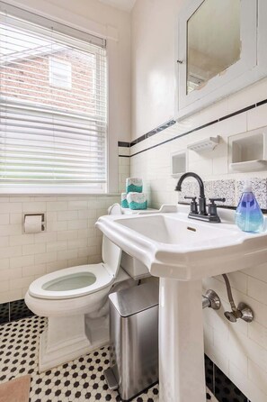 A bathroom with a toilet, sink, and window. - Bright, clean spacious 2 BR apt off street parking (Wilmington)