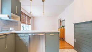 A modern kitchen with grey cabinets, stainless steel dishwasher, and pendant lighting. - Bright, clean spacious 2 BR apt off street parking (Wilmington)