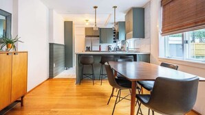 A modern kitchen with a dining area, wooden flooring, and a window with blinds. - Bright, clean spacious 2 BR apt off street parking (Wilmington)