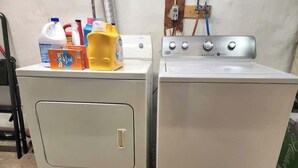 A front-loading washer and dryer stacked on a concrete floor with cleaning supplies on top. - Bright, clean spacious 2 BR apt off street parking (Wilmington)