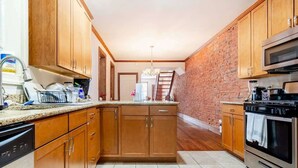 Una cocina con gabinetes de madera, estufa de acero inoxidable y pared de ladrillo.