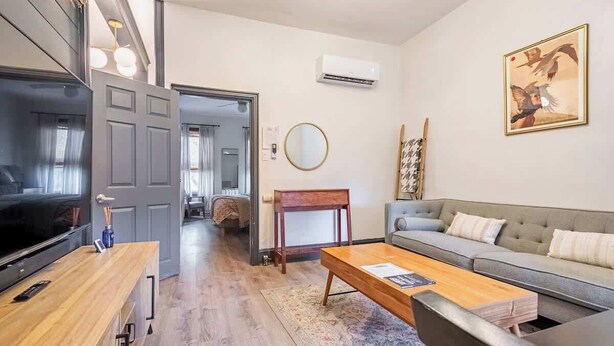 Una sala de estar moderna con sofá, mesa de centro, televisor y un mueble de madera.