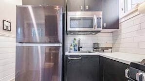 Una cocina compacta con un refrigerador de acero inoxidable, un microondas y un horno empotrado.