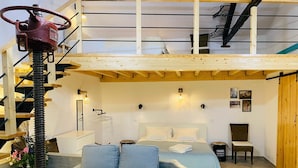 Ett sovrum i loftstil med en våningssäng, en soffa och en trätrappa.