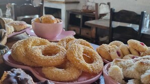 A table with various pastries and desserts, including doughnuts and chocolate-covered items, in a room with a fireplace and a clock on the wall. - Pousada Cafuné  (Socorro)