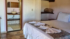 A bedroom with a bed, a bathroom with a sink, and a tiled floor. - Pousada Cafuné  (Socorro)