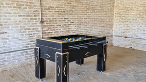 A foosball table in a room with brick walls and a concrete floor. - Pousada Cafuné  (Socorro)