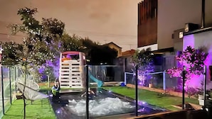 Un modelo de piscina con fuente, rodeada por una valla y diferentes plantas.