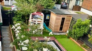Un jardín en la azotea con un área de juegos pequeña, una cancha de baloncesto y una estructura de madera.