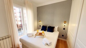 A hotel room with a large bed, a patterned wall, and a view of buildings outside. - Collection Madrid Rio Exterior 3 Personas (Madrid)