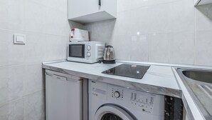 Una cocina compacta con lavadora, microondas y cafetera.