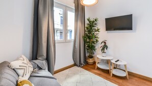 Una sala de estar moderna con un sofá, un televisor, una mesita y una planta en maceta.
