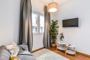 A modern living room with a sofa, a TV, a small table, and a potted plant. - C Plaza de Espa a 3A (Madrid)