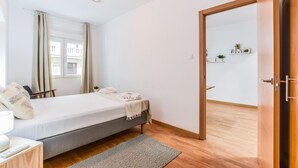 Un dormitorio con cama, mesita de noche, lámpara y vistas al exterior a través de una ventana.