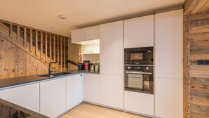 A modern kitchen with white cabinets, a wooden accent wall, and stainless steel appliances.