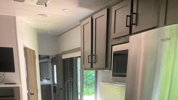 Una cucina compatta con frigorifero in acciaio inox, forno a microonde, fornello e lavello.