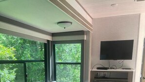 Interni di un camper compatto con divano, televisore a schermo piatto e angolo cottura.