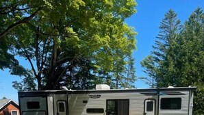 Un camper con un patio, completo di sedute all'aperto e un tavolino.