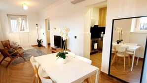 A dining area with a white table and chairs, a vase with flowers, and a large mirror reflecting the room. - Collection Madrid R o Est Ndar 4 Personas (Madrid)