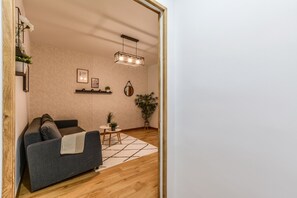 Un salon moderne avec un canapé gris, une petite table ronde et une plante en pot.
