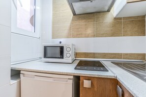 Una cocina moderna con armarios blancos, un microondas integrado, una placa de inducción y una ventana sobre el fregadero.