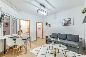 A modern living room with a grey sofa, a dining table with chairs, a coffee table, and a pendant light. - C Plaza de Espa a 4B (Madrid)