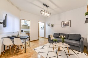 A modern living room with a grey sofa, a dining table with chairs, a kitchen in the background, and a large mirror on the wall. - C Plaza de Espa a 4B (Madrid)
