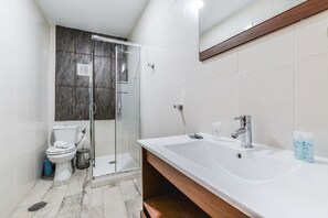 A modern bathroom with a glass-enclosed shower, a white sink with a wooden vanity, and a toilet. - C Plaza de Espa a 4B (Madrid)