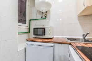 A compact kitchen with a microwave, a sink, and a dishwasher. - C Plaza de Espa a 4B (Madrid)