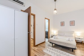 Un dormitorio con cama, mesitas de noche, armario y puerta de acceso a un baño.