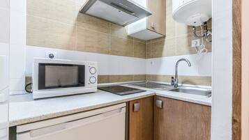 A modern kitchen with a microwave, stove, sink, and wooden cabinets.