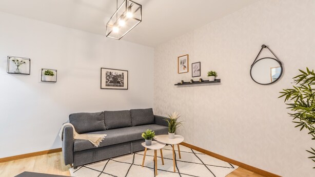 A modern living room with a grey sofa, a small round table with two chairs, a geometric rug, and a hanging light fixture. - C Plaza de Espa a 4B (Madrid)