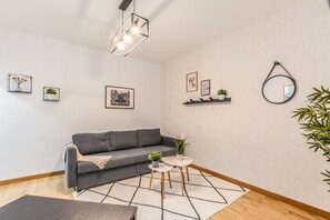 A modern living room with a grey sofa, a small round table with two chairs, a geometric rug, and a hanging light fixture. - C Plaza de Espa a 4B (Madrid)
