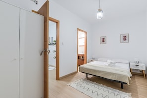 A bedroom with a bed, bedside tables, a wardrobe, a mirror, and a door leading to another room. - C Plaza de Espa a 4B (Madrid)