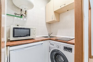 A compact kitchenette with a microwave, sink, and washing machine. - C Plaza de Espa a 4B (Madrid)