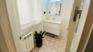 A small bathroom with a white sink, a mirror, and a potted plant. - C Madrid R o 2 F in Madrid (Madrid)