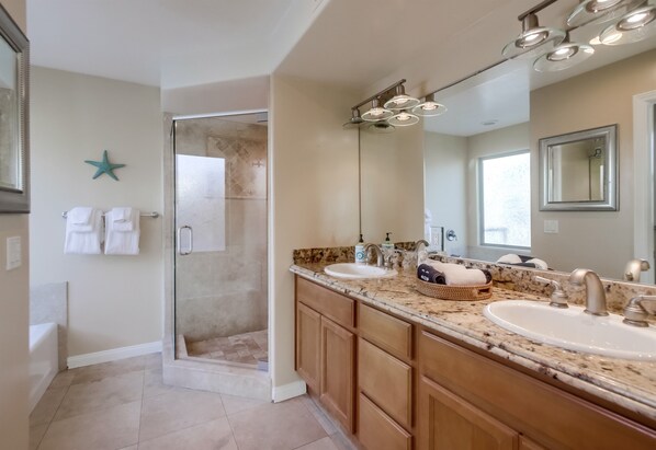 Un baño moderno con ducha de vidrio, lavamanos dobles, armarios de madera y un espejo grande.
