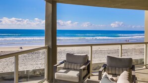 Ein Balkon mit zwei Stühlen mit Blick auf einen Strand.