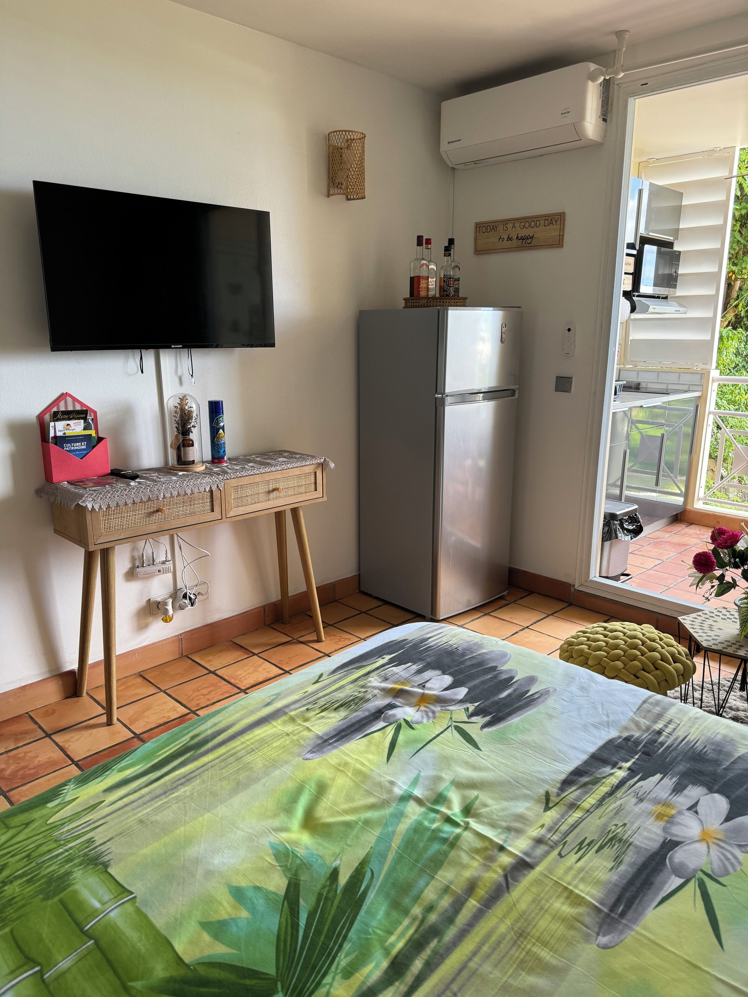 Cocina compacta con refrigerador, televisor de pantalla plana y una mesita con una cesta.