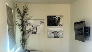 Un salon avec un canapé, une petite table et un téléviseur fixé au mur.
