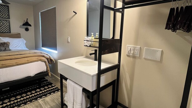 Une chambre à coucher de taille modeste, avec un lit, un lavabo blanc et un miroir.