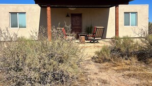 Un bâtiment moderne doté d’un patio couvert, d’une porte en bois et d’une chaise à l’extérieur.