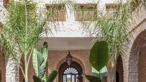 A courtyard with a fountain, potted plants, and a stone wall. - Villa Riad Dharma (Essaouira)